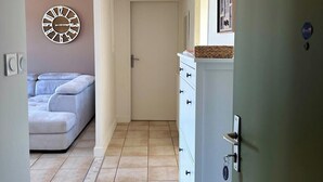 A hallway with a white door, a white dresser with drawers, and a beige sofa in the background. - Casa Ribot #10 - T4 pour 5 personnes - Proche Centre Ville (Brive-la-Gaillarde)