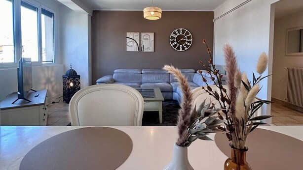 A modern living room with a round table, a sofa, and a large window. - Casa Ribot #10 - T4 pour 5 personnes - Proche Centre Ville (Brive-la-Gaillarde)