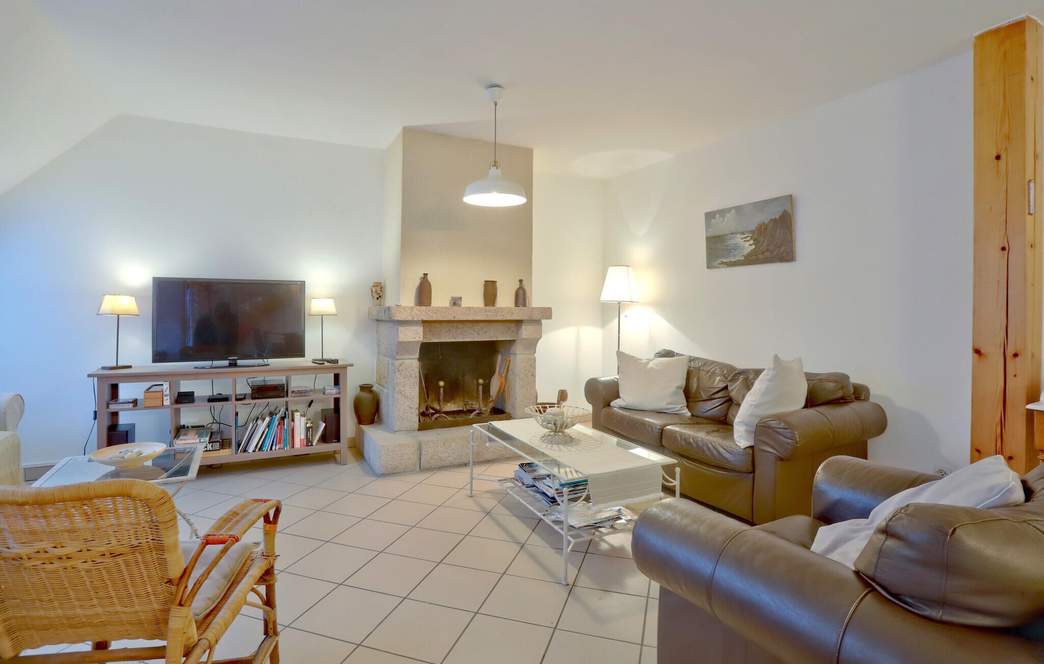 A living room with a television, bookshelves, a fireplace, a sofa, and a dining table.