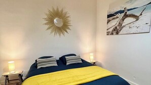 Een slaapkamer met een bed, twee bedlampjes, een spiegel aan de muur en een schilderij.