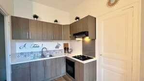 Een kleine keuken met houten kastjes, een inbouwfornuis en een witte wasbak.