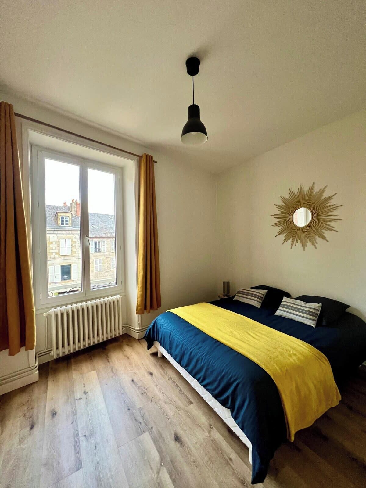 Un dormitorio con cama, un radiador, una ventana con cortinas y una lámpara en el techo.