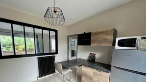 A modern kitchen with a black countertop, stainless steel appliances, and a window overlooking greenery.