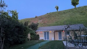 Una casa con techo inclinado, un porche delantero y un pequeño jardín con un sendero.