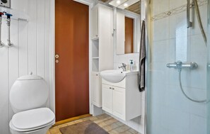 A bathroom with a toilet, a sink, a mirror, and a shower.