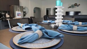 Ein Esstisch, gedeckt mit blauen Servietten, Tellern und einem weißen Kerzenständer.
