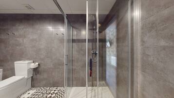 Une salle de bain moderne avec une douche à parois de verre, des toilettes et un carrelage décoratif.