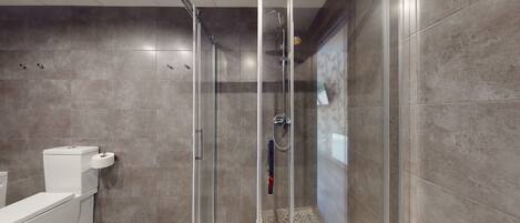 Un baño moderno con cabina de ducha de vidrio, inodoro y suelo estampado.