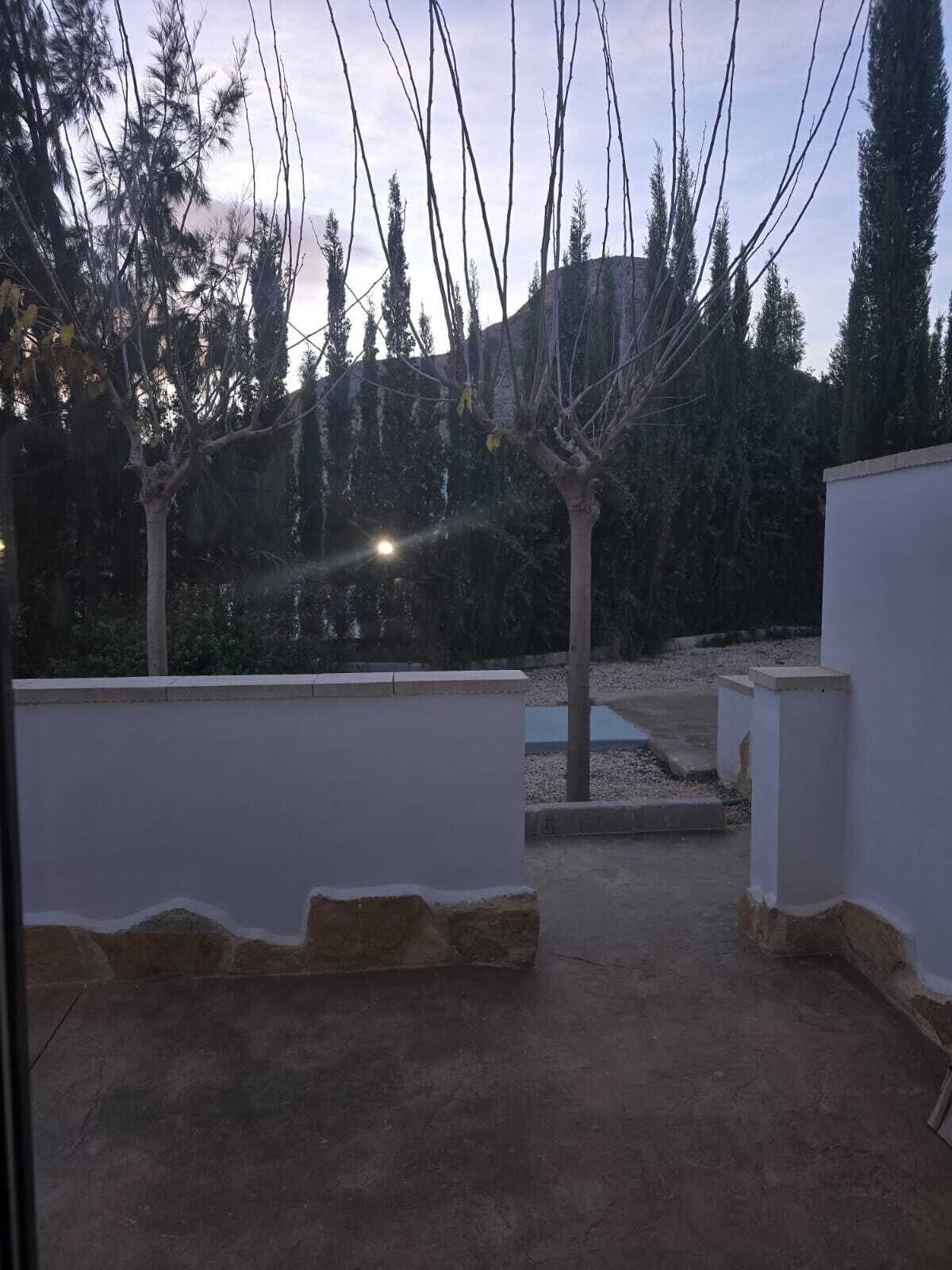 An outdoor patio area with a concrete floor, white walls, and a small water feature.