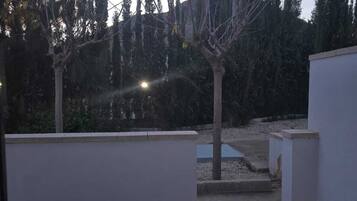 Un patio al aire libre con suelo de hormigón, paredes blancas y una pequeña fuente de agua.