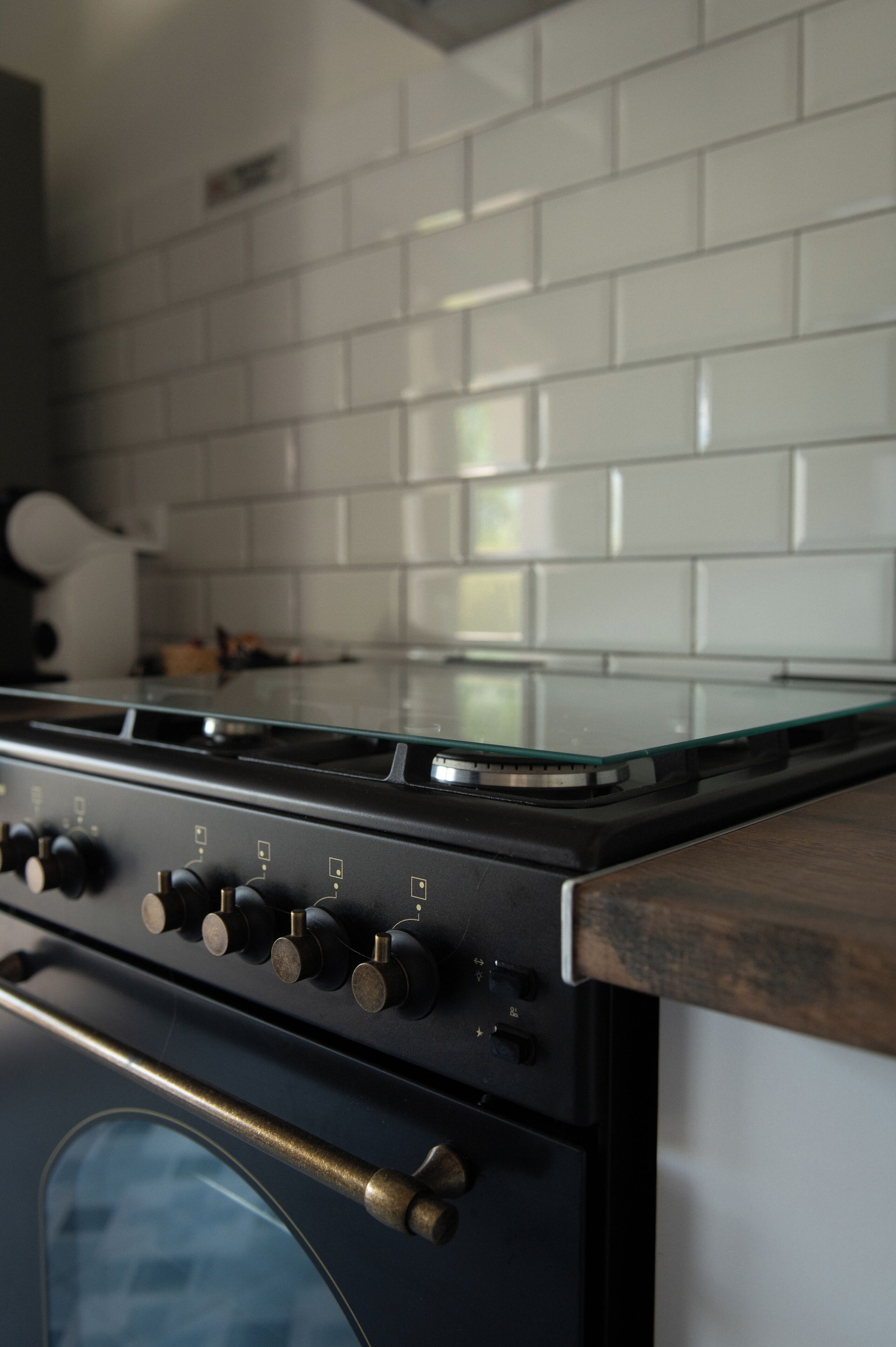 Una cocina con estufa, horno y salpicadero de azulejos blancos.