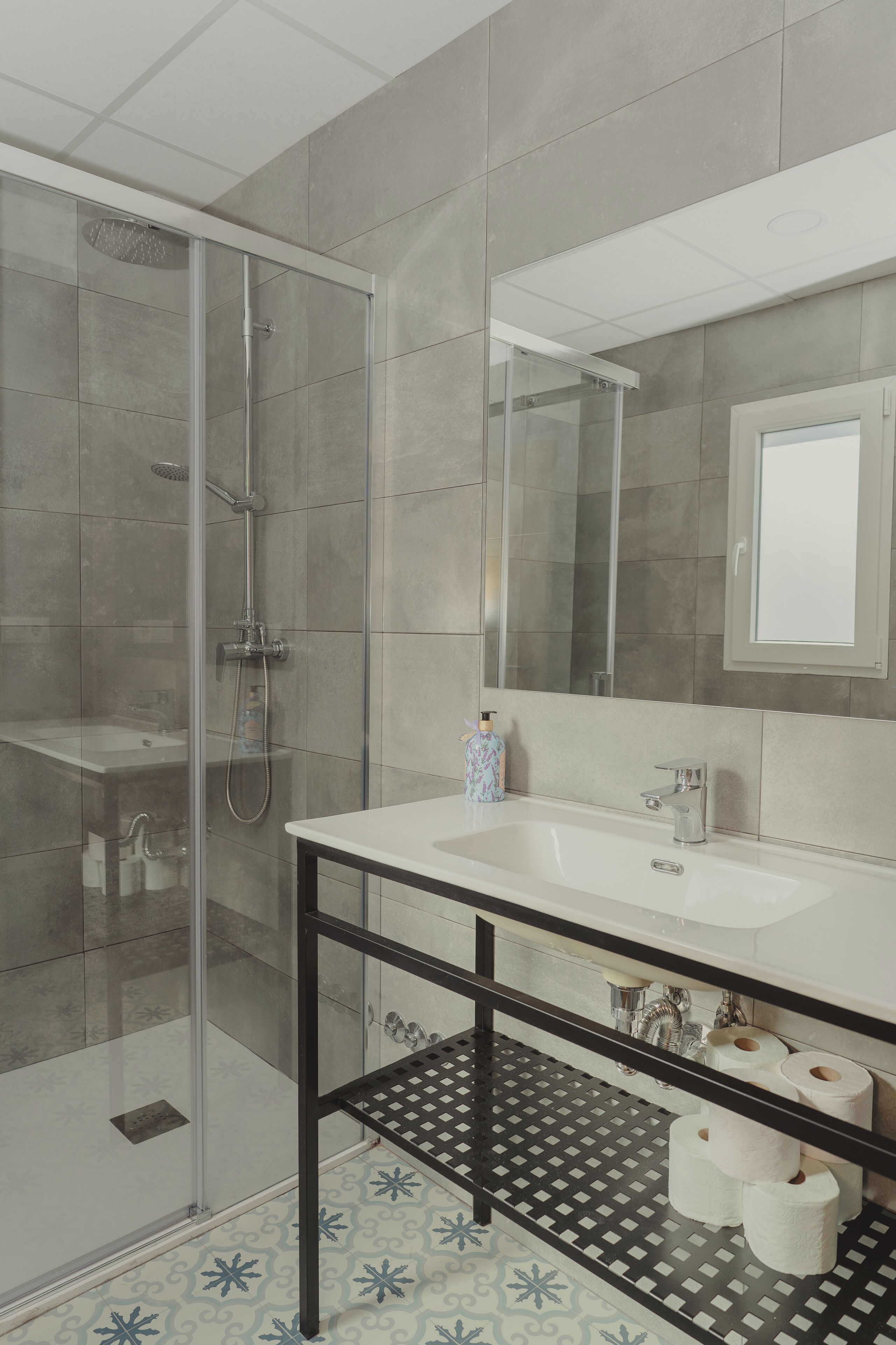 A modern bathroom with a glass-enclosed shower, a white sink, and a mirror above it.