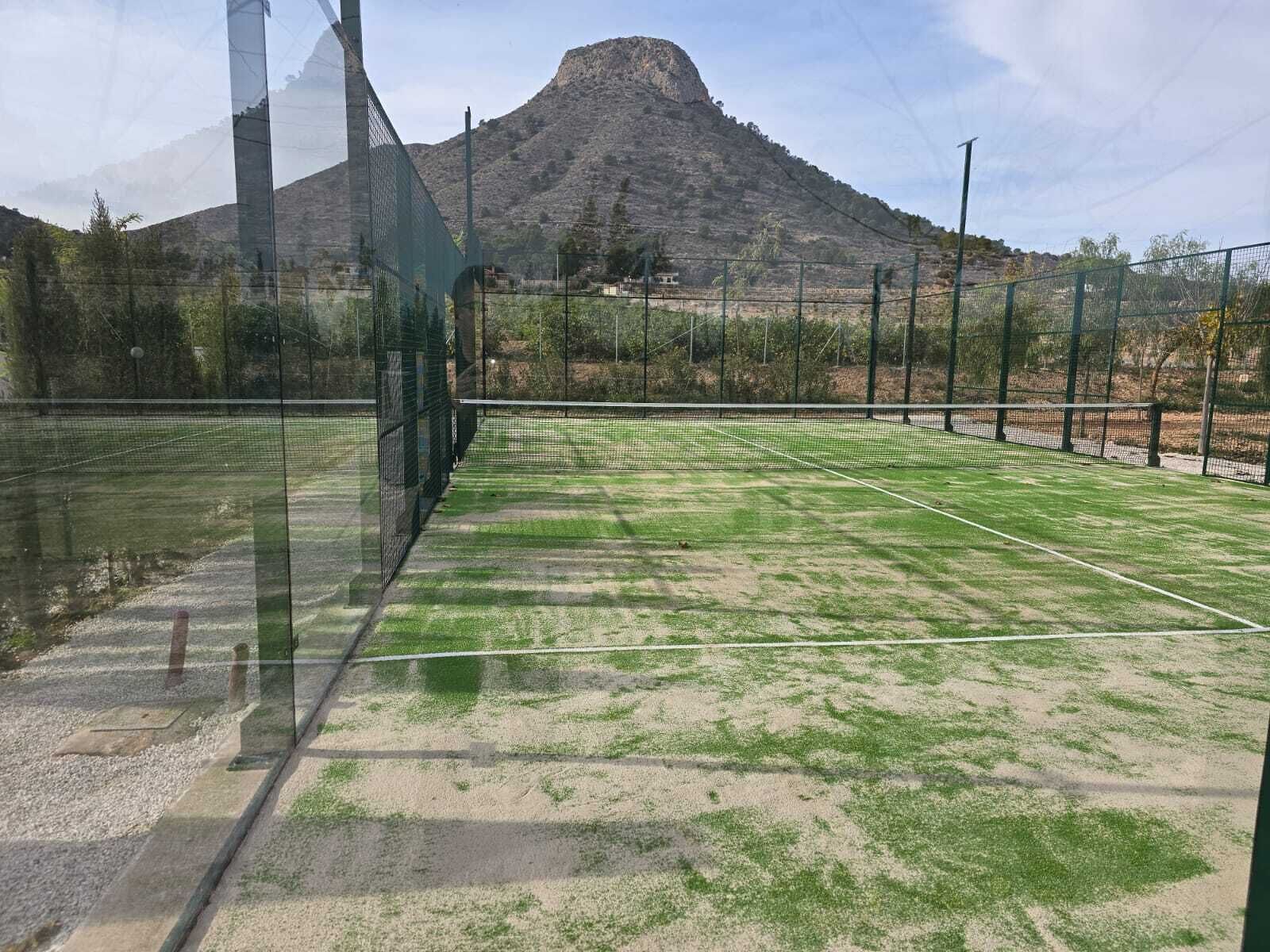 An outdoor tennis court with a mountain in the background.