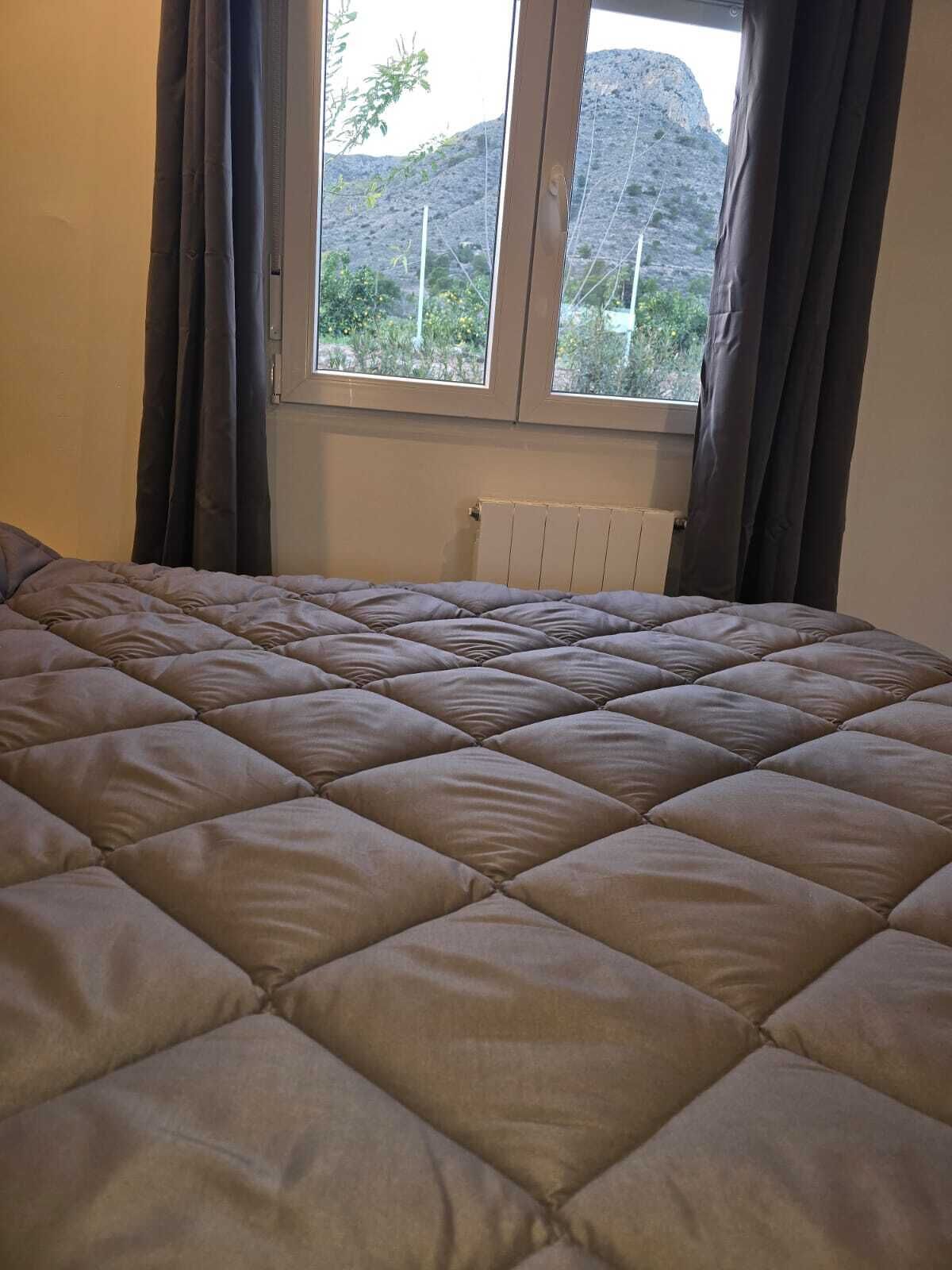 A bedroom with a large bed, a window with curtains, and a radiator.