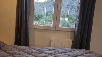 Un dormitorio con una cama grande, una ventana con cortinas y un radiador.