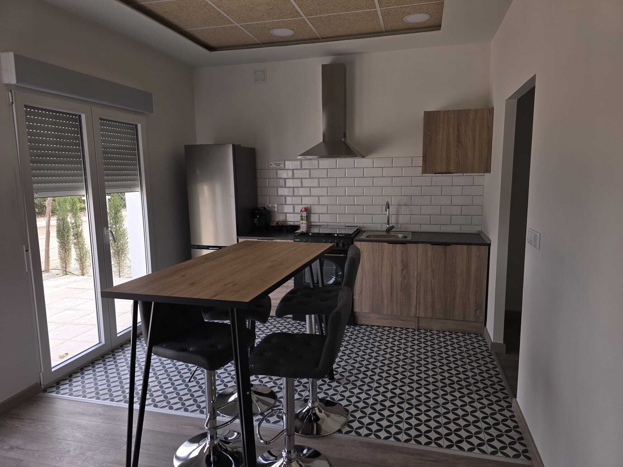 Cocina compacta con comedor, que incluye un refrigerador de acero inoxidable, estufa a gas y un mueble de madera.