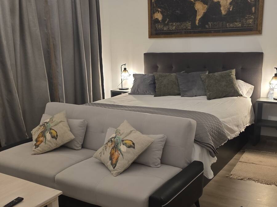 A bedroom with a bed, a sofa, a desk, and a chair.