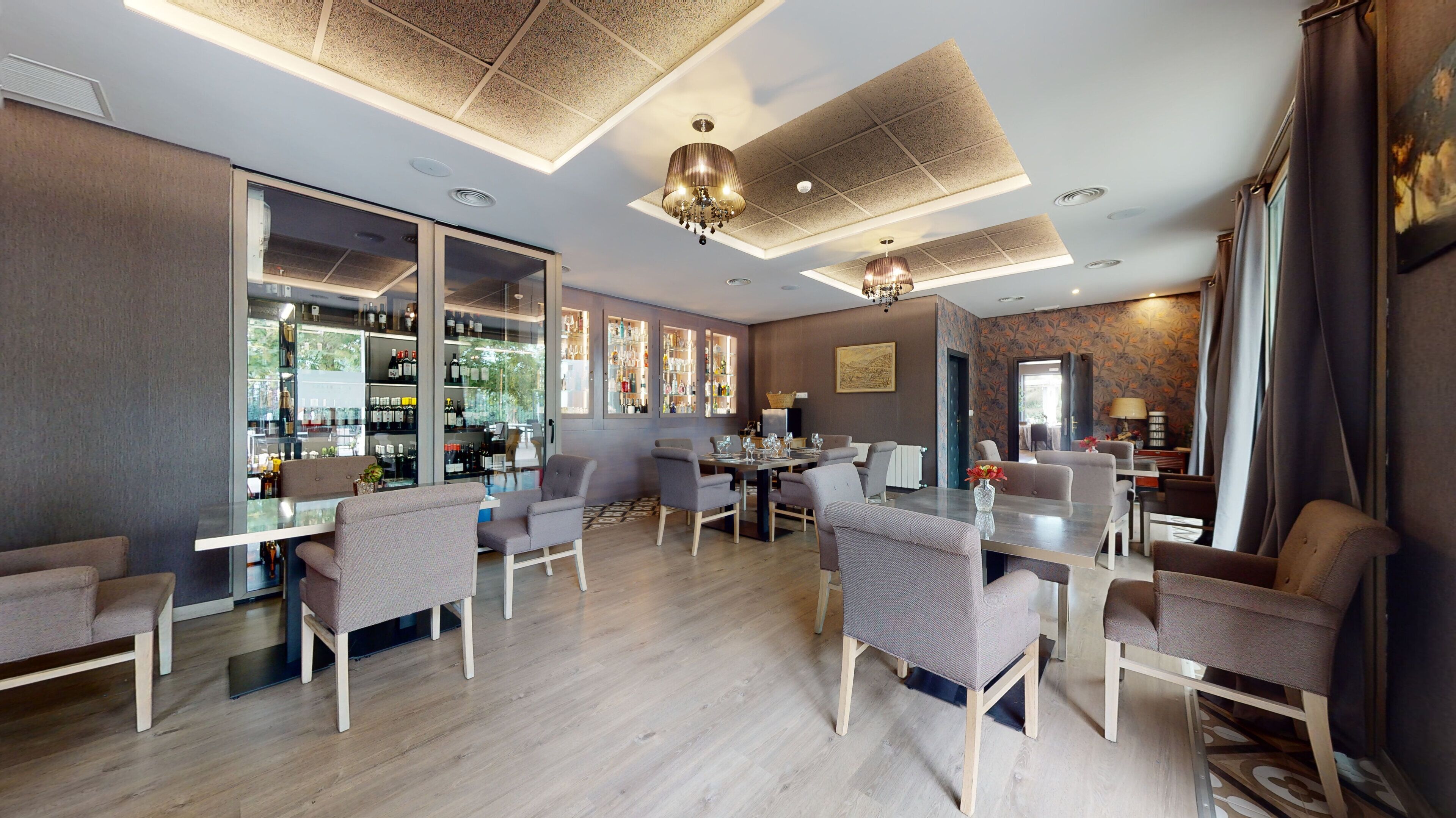 Un comedor moderno de hotel con bar, asientos y vistas a la ciudad.