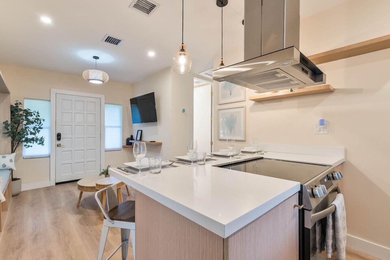 A modern kitchen with a central island, built-in oven, and a dining area with a small table and chairs.