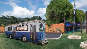 A streetcar named Desire parked on grass with a building and trees in the background. - Liberty Hill Executive Inn (Zephyrhills)