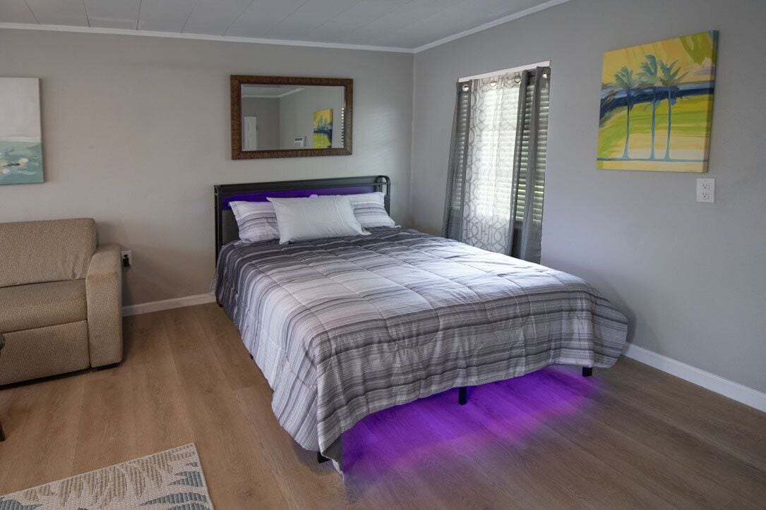 Une chambre à coucher avec un lit, un canapé, un miroir et des œuvres d’art accrochées aux murs.