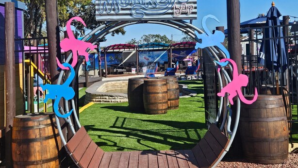 A playground area with a sign for "Two Naked Monkey's Bar" and a wooden structure with a curved roof. - Liberty Hill Executive Inn (Zephyrhills)