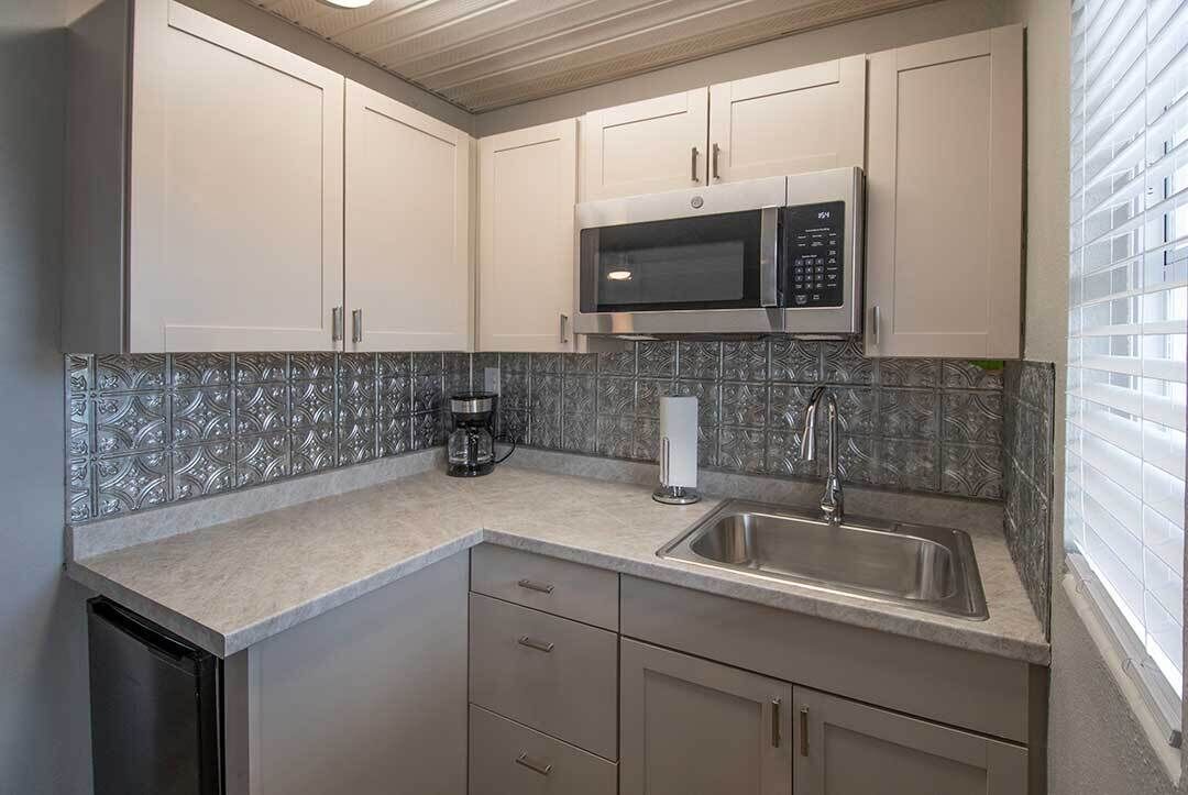 Una cocina moderna con electrodomésticos de acero inoxidable, microondas integrado y cafetera.