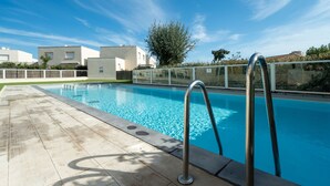 Ein Schwimmbecken mit Holzterrasse, Metallleiter und blauem Himmel.