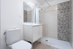 Une salle de bain moderne équipée de toilettes, d’un lavabo et d’une douche.