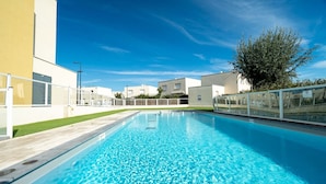 A rectangular swimming pool with clear blue water, surrounded by a white fence and a grassy area. - Bright Villa Steps from the Sea (Sérignan)