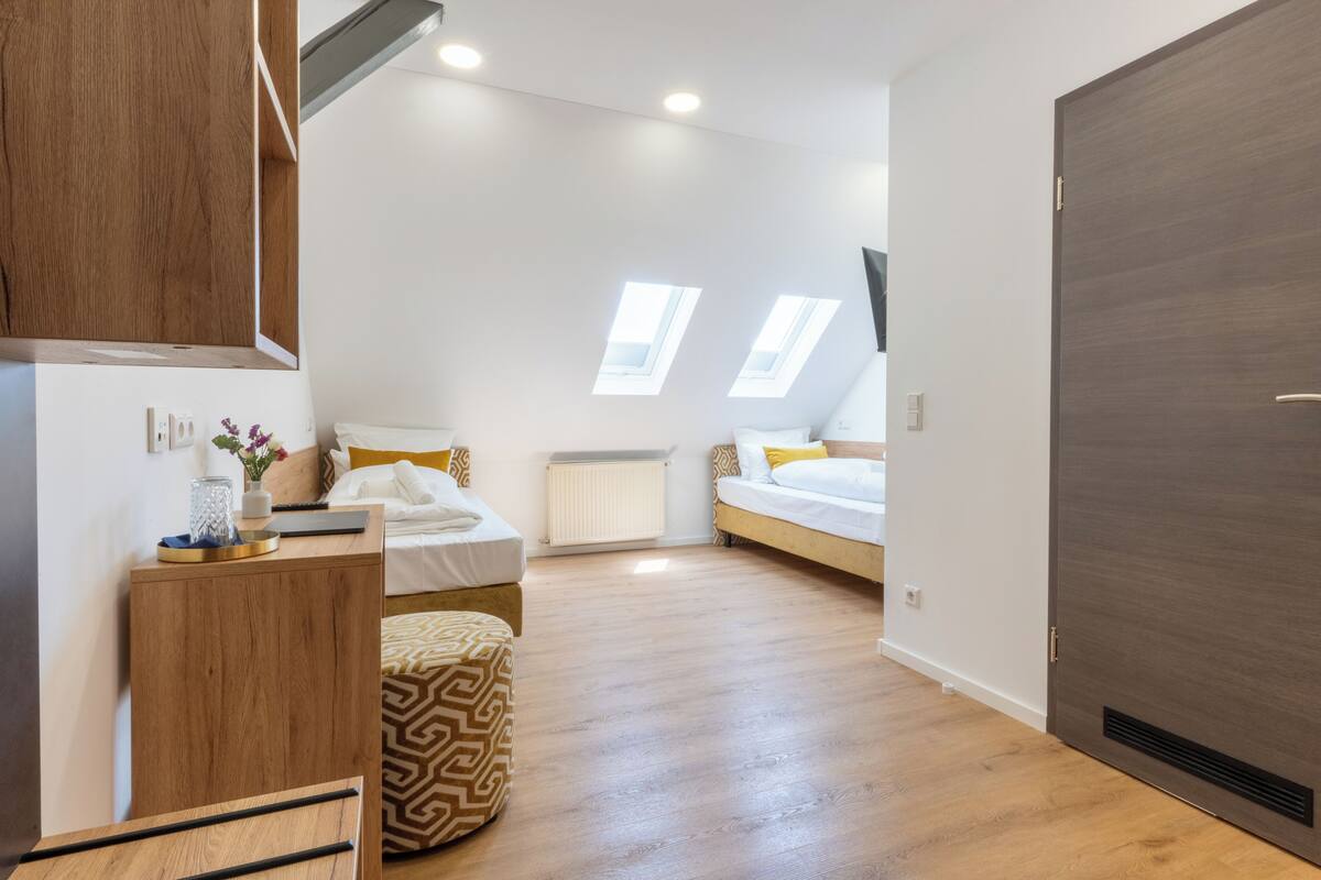 Een moderne slaapkamer met twee bedden, een houten bureau, een radiator en dakramen.