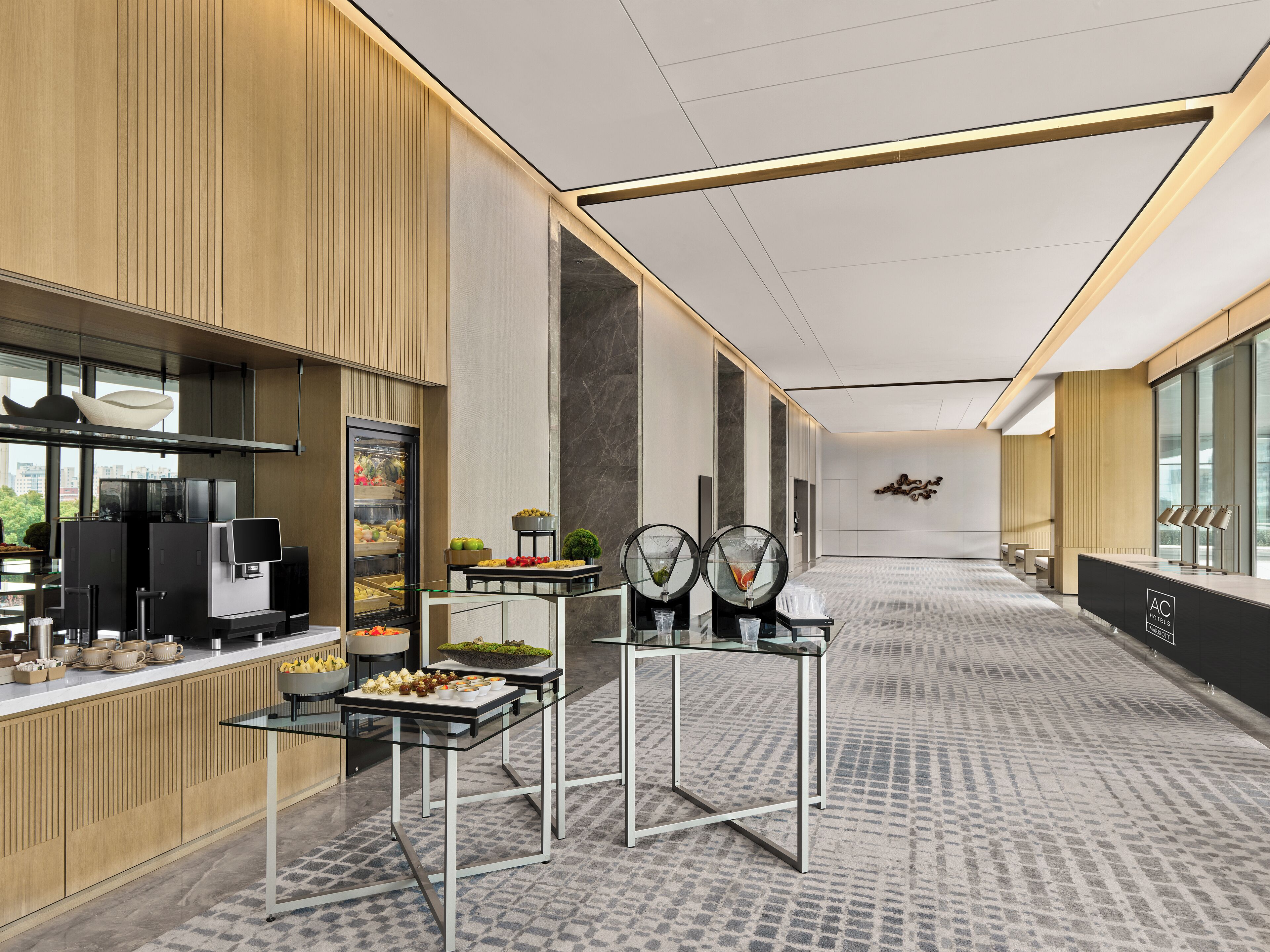 A modern hotel lobby with a buffet area, a reception desk, and a seating area.