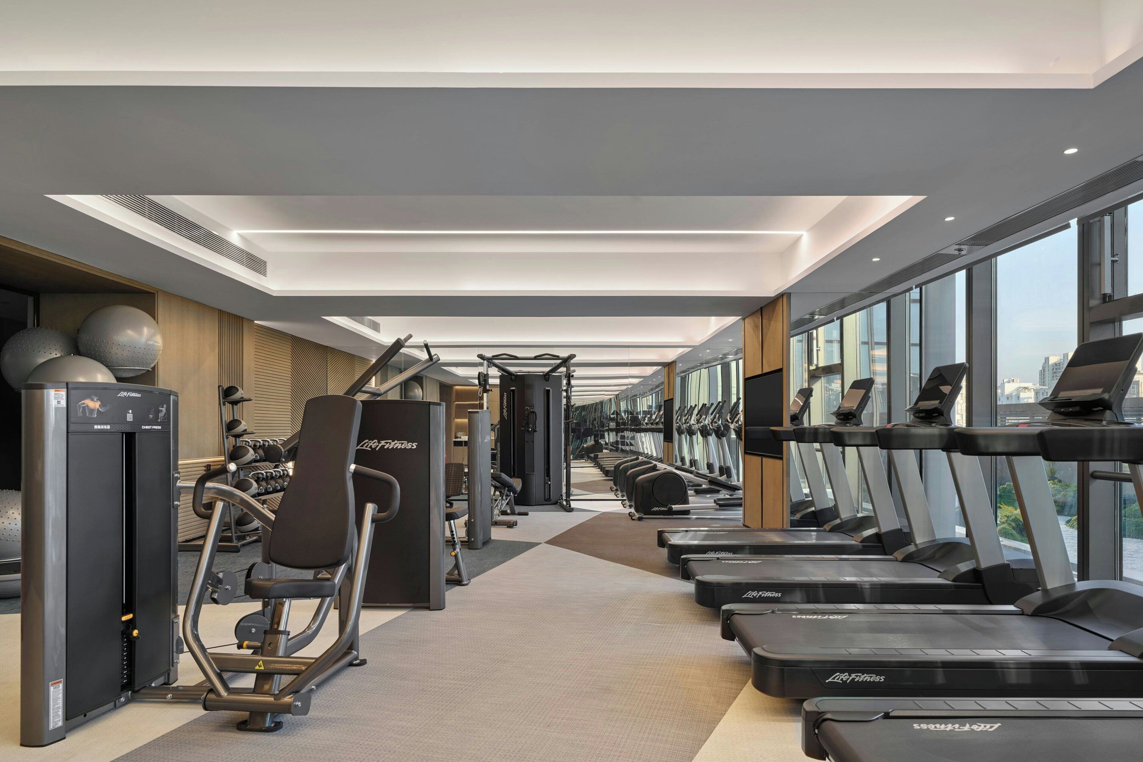 Een moderne sportschool met loopbanden, krachtapparaten en fitnessballen.