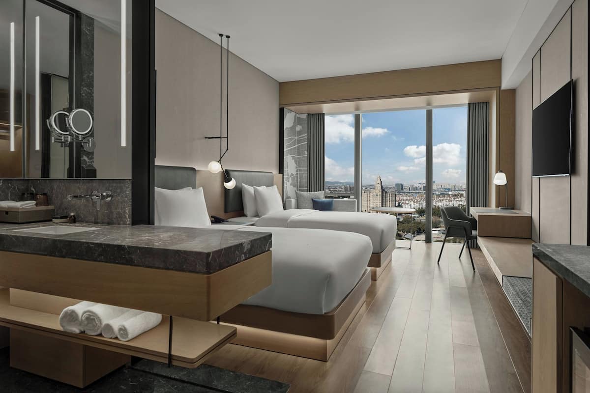 Une chambre d’hôtel moderne dotée d’un grand lit, d’un bureau, d’une chaise, d’une télévision et offrant une vue sur la ville.