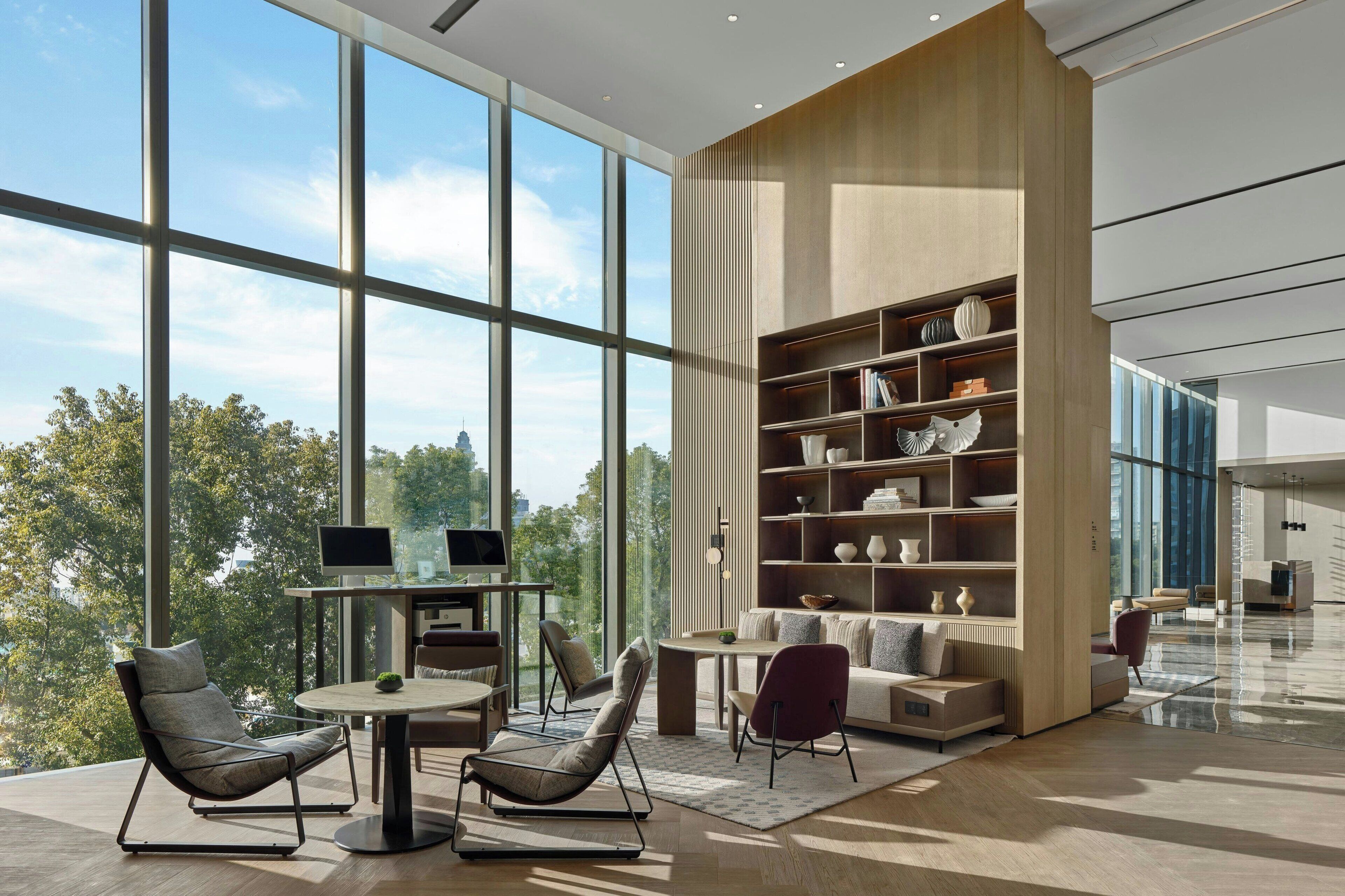 A modern interior with large windows, a wooden bookshelf, and contemporary furniture.
