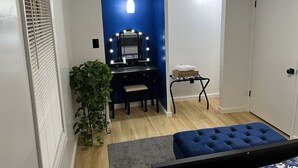 A compact room with a vanity, mirror, and a small ironing board.