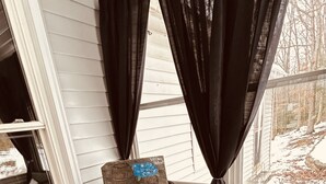 A cozy corner with two wicker chairs, a wooden barrel, and a window with curtains.
