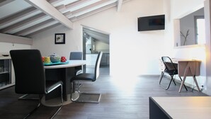 A modern kitchen with a dining area, a TV mounted on the wall, and a staircase leading to an upper level. - SEGURAKO BORDA - URRUGNE (URRUGNE)