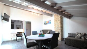 A modern dining area with a round table, black chairs, and a stone accent wall. - SEGURAKO BORDA - URRUGNE (URRUGNE)