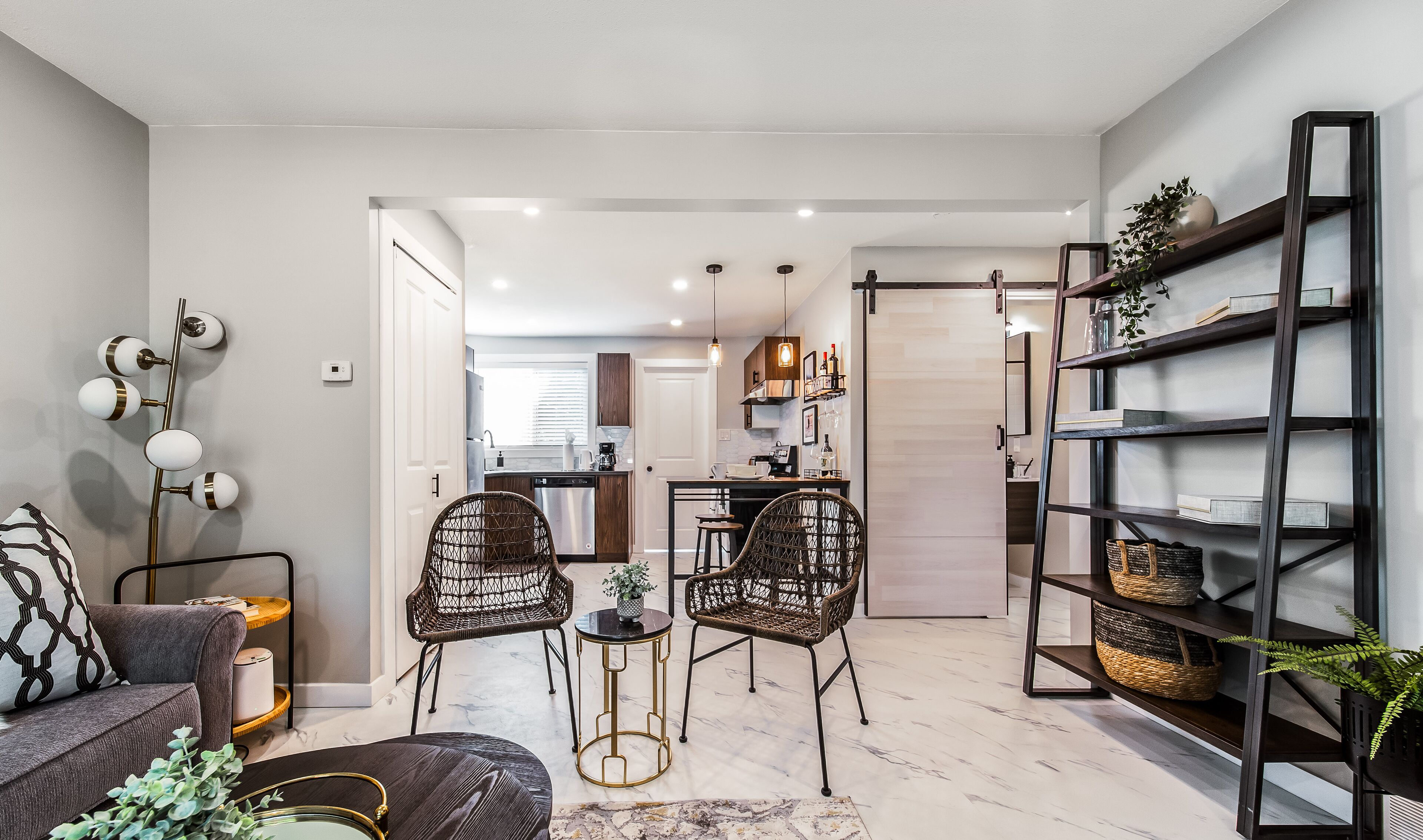 Uma sala de estar moderna com cadeiras de vime, um sofá e uma estante.