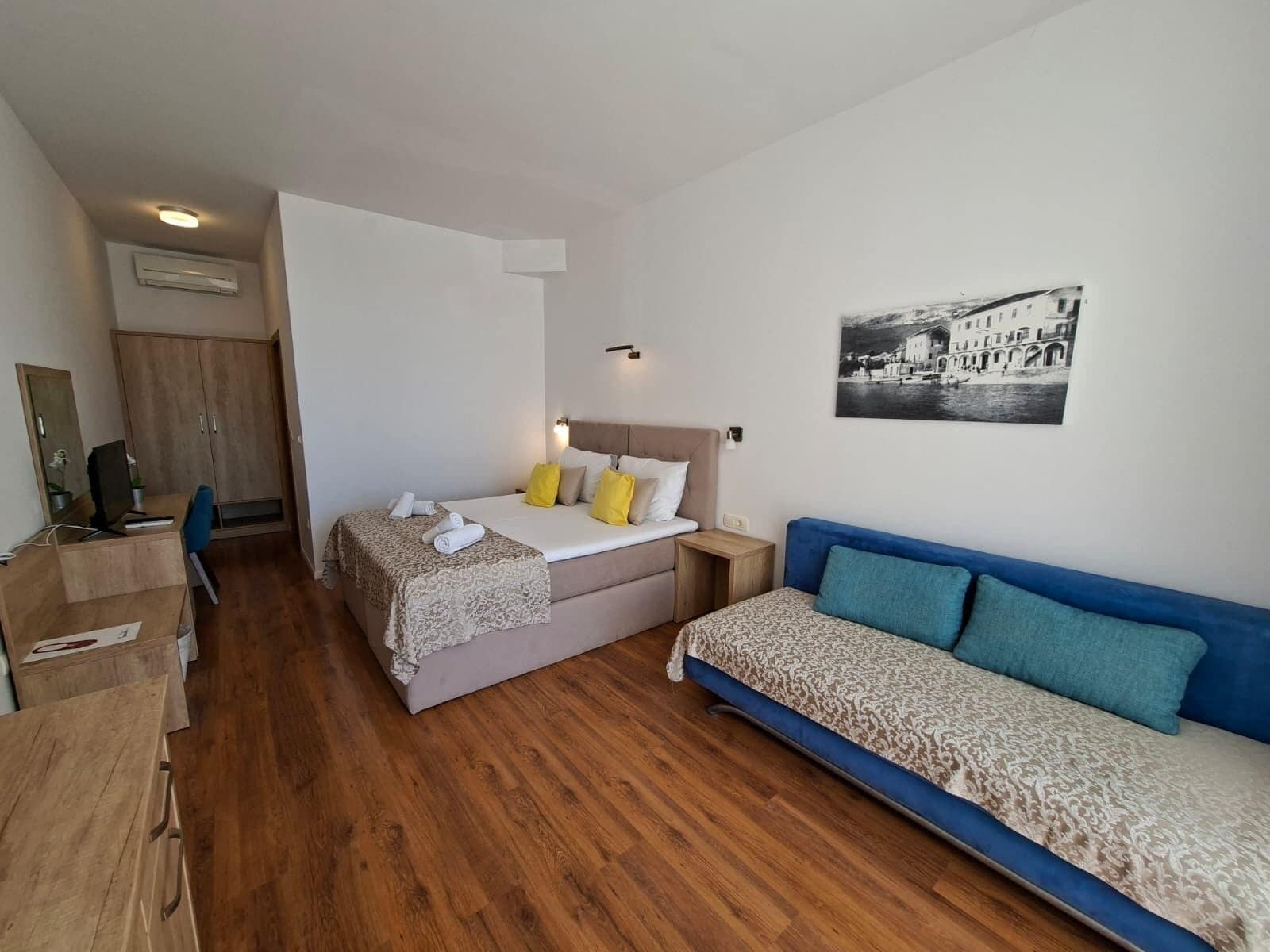 A bedroom with a bed, a desk, a chair, a wardrobe, and a sofa.