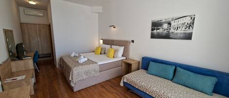 A bedroom with a bed, a desk, a chair, a wardrobe, and a sofa.