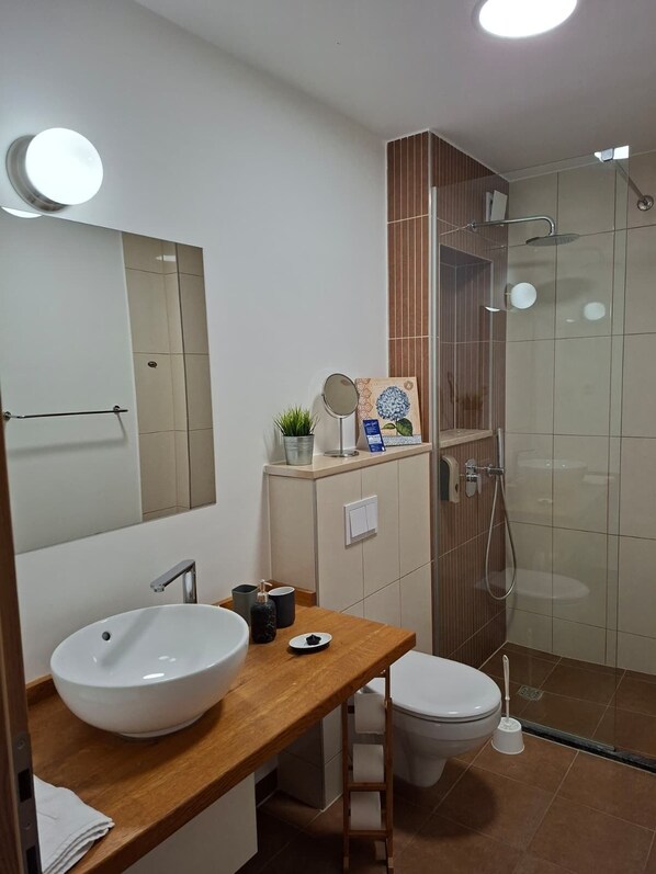 A modern bathroom with a large mirror, a sink, a toilet, and a shower. - Villa Cascada (Podgora)