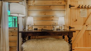 A wooden interior with a table, two lamps, a clock, and a fluffy stool. -  Luxury in the Smokey Mountains with Hot Tub Pet Friendly (Elizabethton)