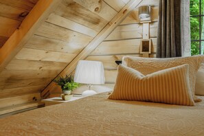 A cozy attic bedroom with wooden walls, a bed with beige bedding, a bedside lamp, and a small potted plant. -  Starry Nights in the Smokey Mountains with Hot Tub Pet Friendly (Elizabethton)