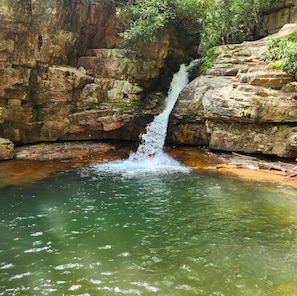 A waterfall cascading into a pool surrounded by rocky terrain.