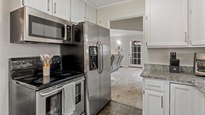 A modern kitchen with stainless steel appliances, white cabinetry, and a granite countertop.