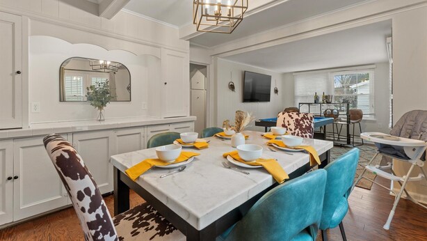 A dining area with a marble table, blue chairs, and a chandelier.