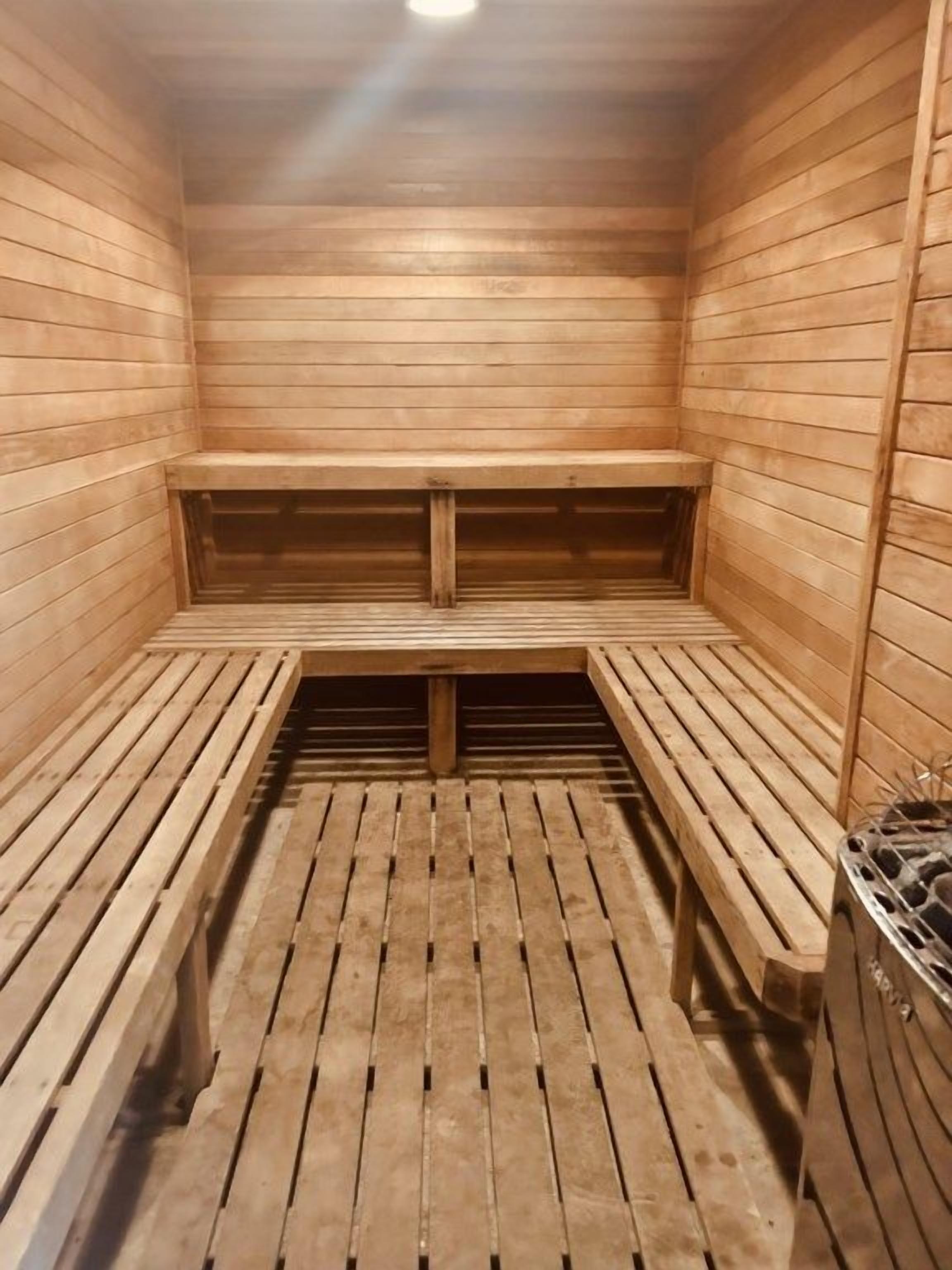 Una sauna con bancos de madera y un banco en el centro.