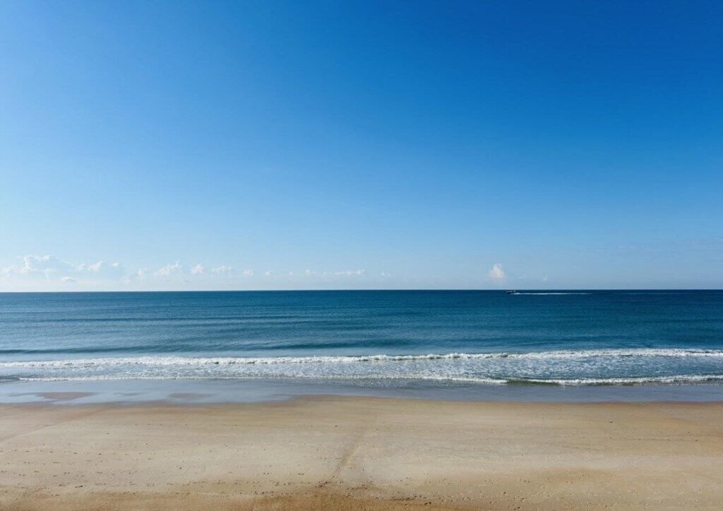Een strand met een heldere lucht en een rustige zee.